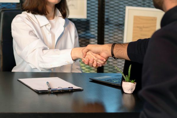 Two people shaking hands across a desk