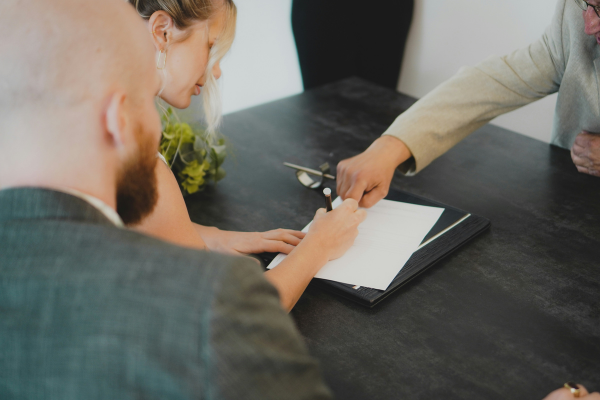 Woman sitting at desk signing paper with pen