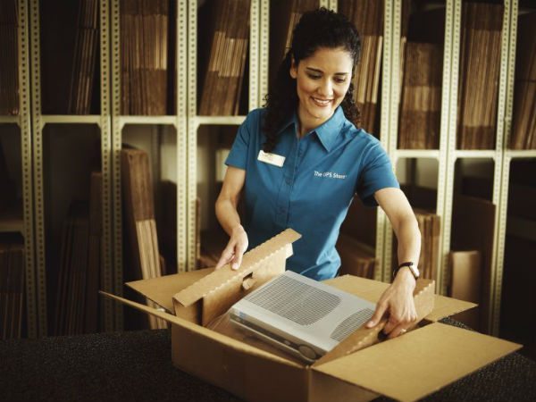 The UPS Store employee packing items in cardboard box