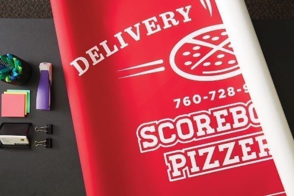 A red banner advertising delivery at a pizza place